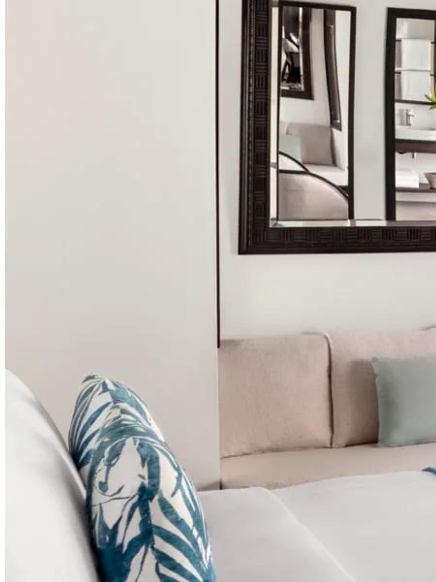 Deluxe Over Water Villa bedroom and lounge with a mirrored dressing area and lagoon-facing deck