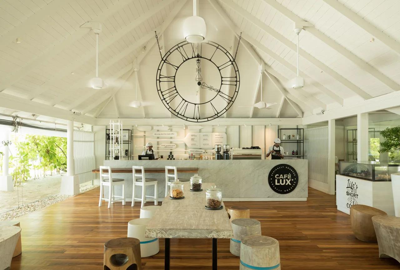 The interior of Cafe LUX*, with its marble counter, oversized wall clock and staff serving coffee