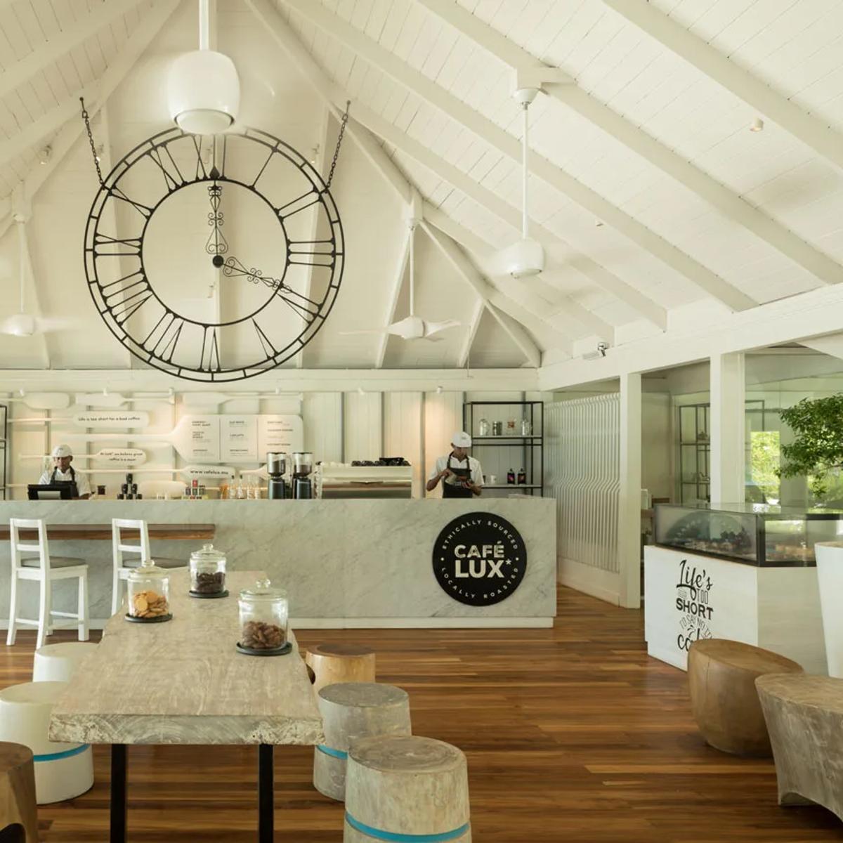 The interior of Cafe LUX*, with its marble counter, oversized wall clock and staff serving coffee