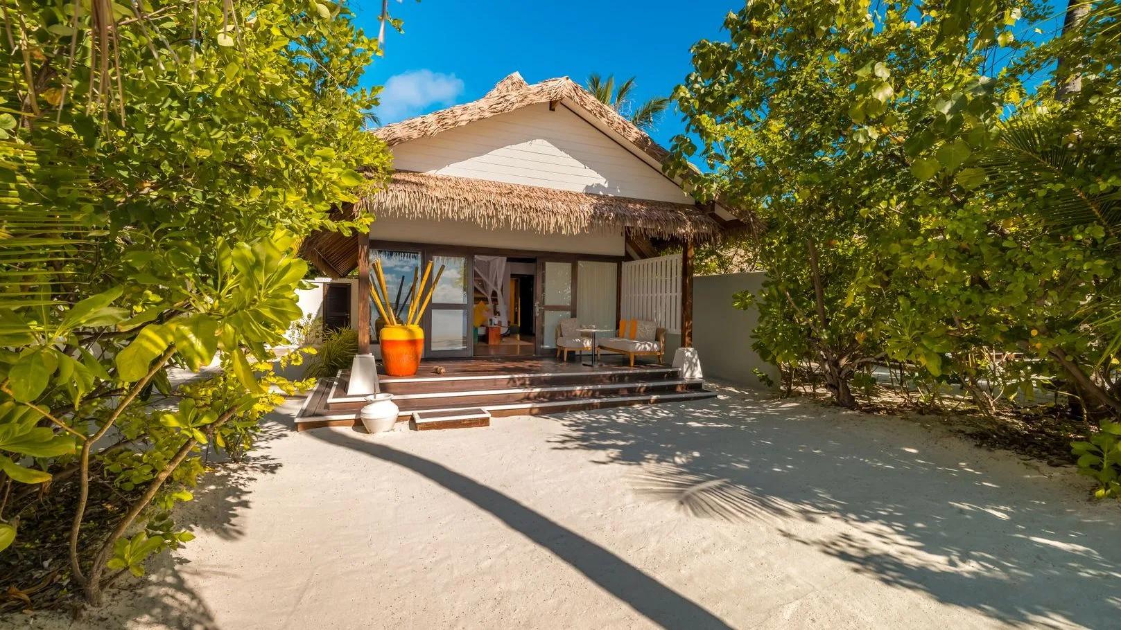 Earth Villa's thatched-roof exterior, reached along a sand path through the garden