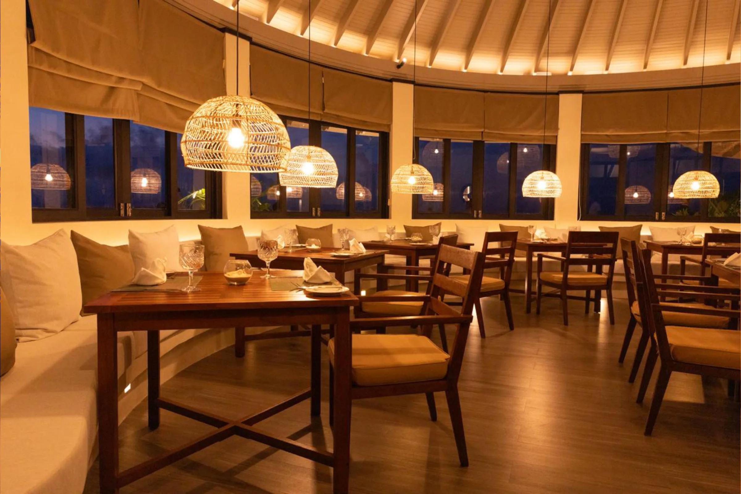 A round dining room lit by pendant lighting at dusk, representative of Iru Fushi's evening specialty restaurants — dedicated Trio photography to follow