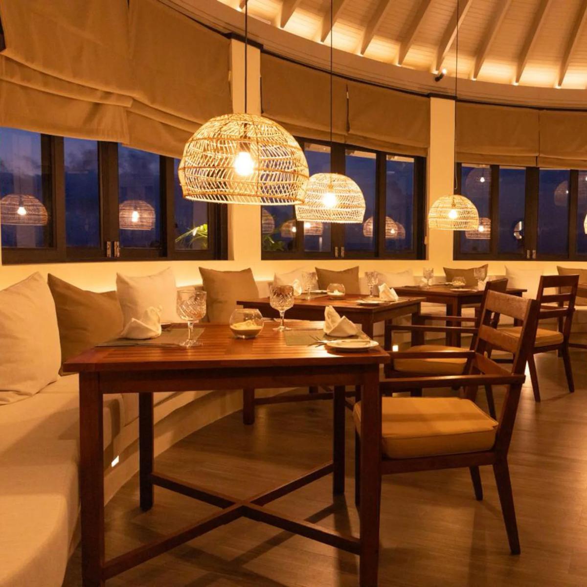 A round dining room lit by pendant lighting at dusk, representative of Iru Fushi's evening specialty restaurants — dedicated Trio photography to follow