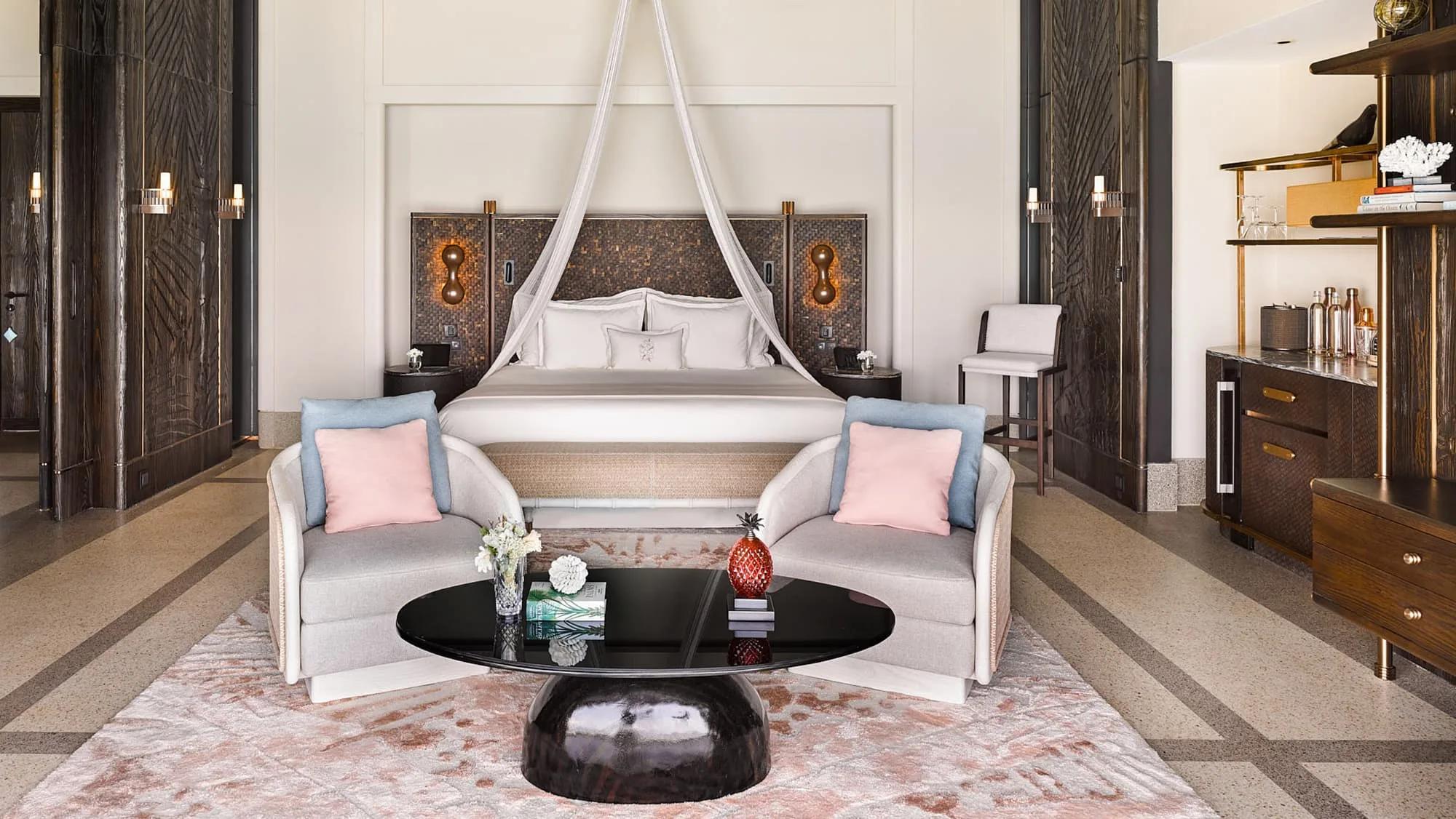 The king bedroom of a Water Villa with Pool, with a sheer canopy over the bed and a dark woven headboard