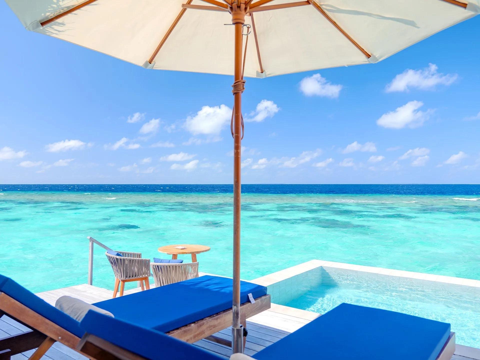A Water Villa with Pool's overwater deck, plunge pool and sun umbrella above the reef at Baglioni Maldives