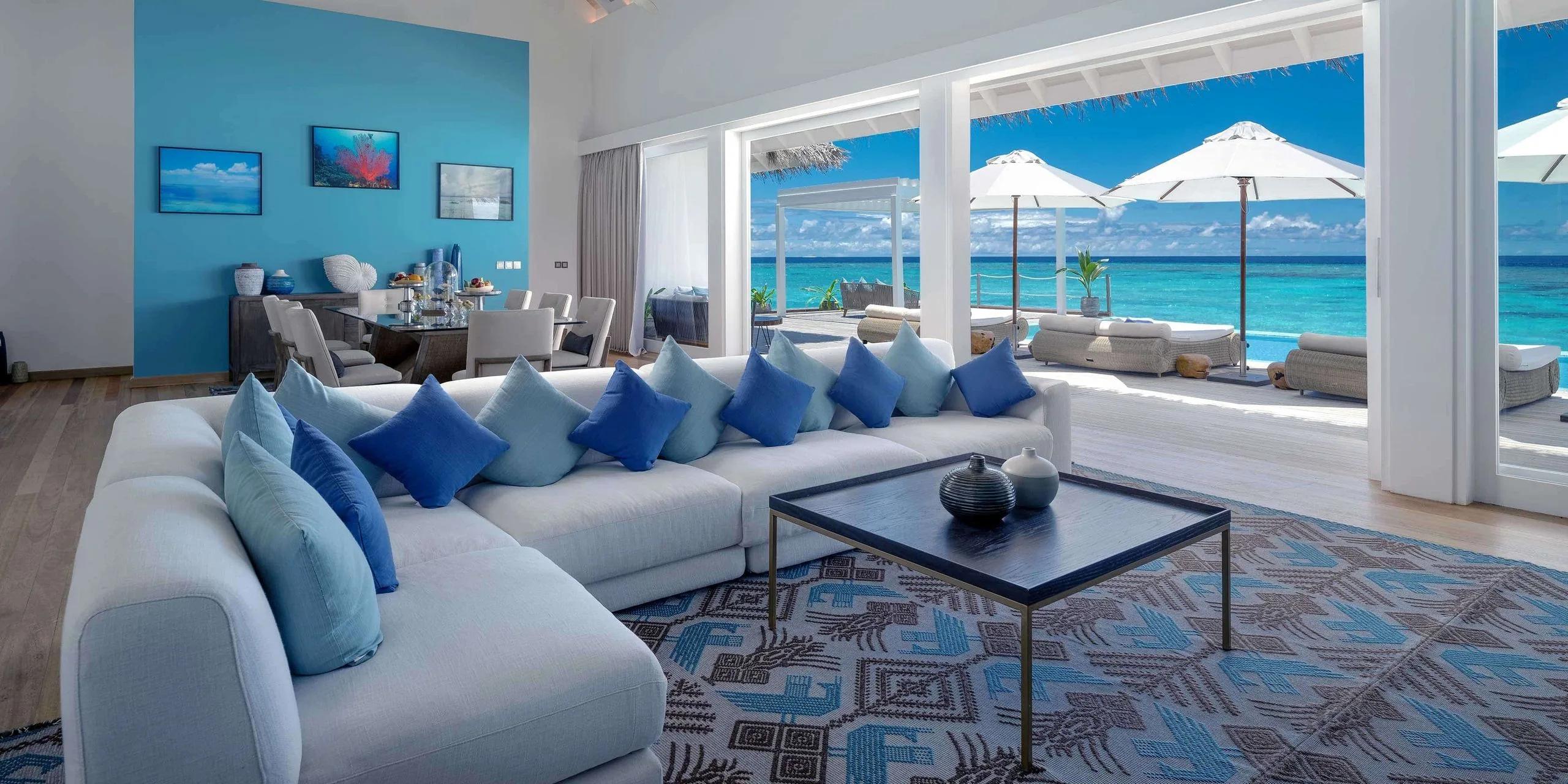 The Grand Baglioni Maldives Villa's living room opening onto its private overwater pool and the open lagoon beyond