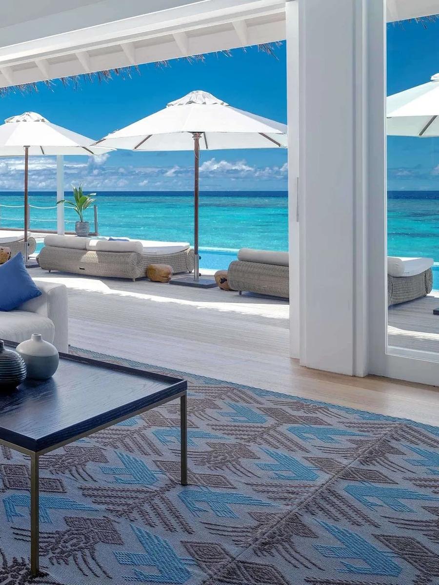 The Grand Baglioni Maldives Villa's living room opening onto its private overwater pool and the open lagoon beyond
