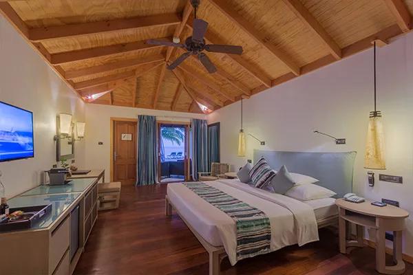 Romantic Beachfront Villa bedroom, with terrace doors opening onto a private deck and beach lounger