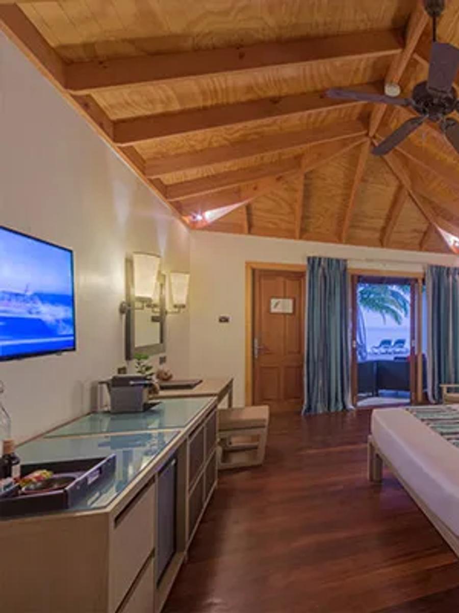 Romantic Beachfront Villa bedroom, with terrace doors opening onto a private deck and beach lounger