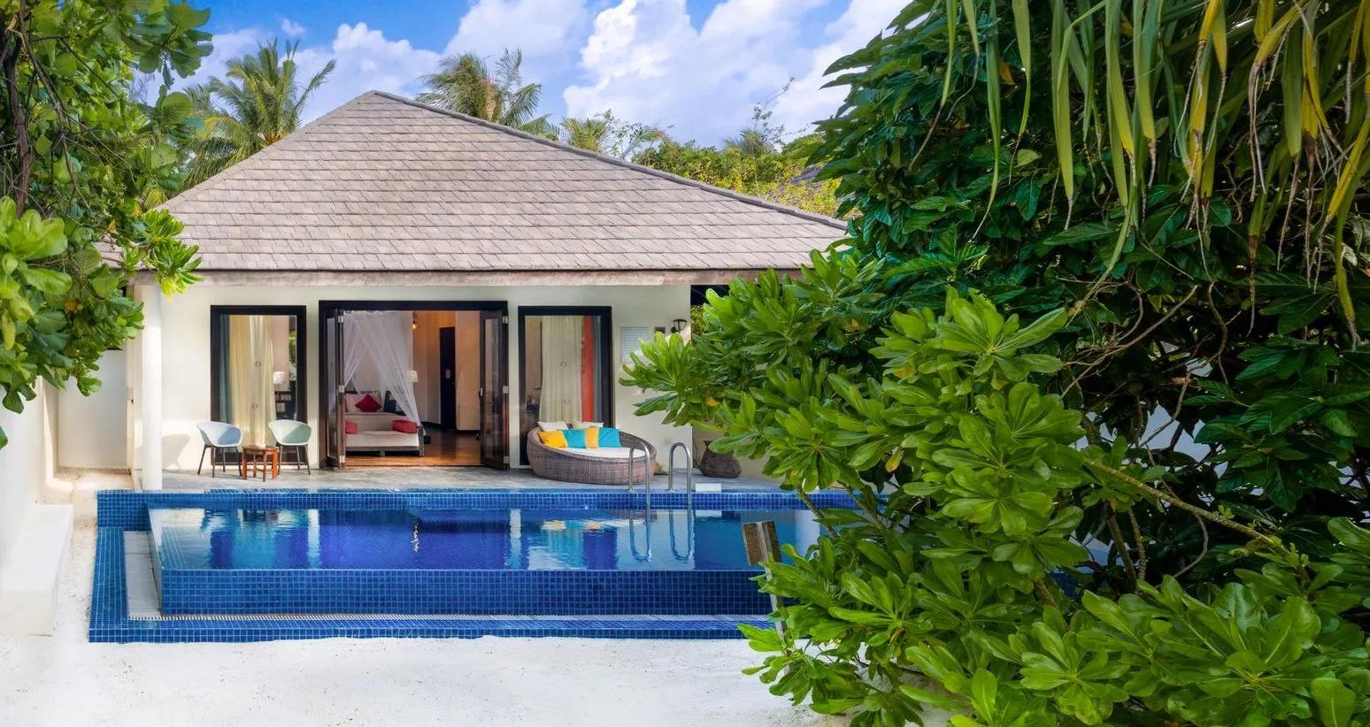 A Sunset Beach Villa with Pool's exterior deck, its private pool and colourful daybed seating just off the bedroom