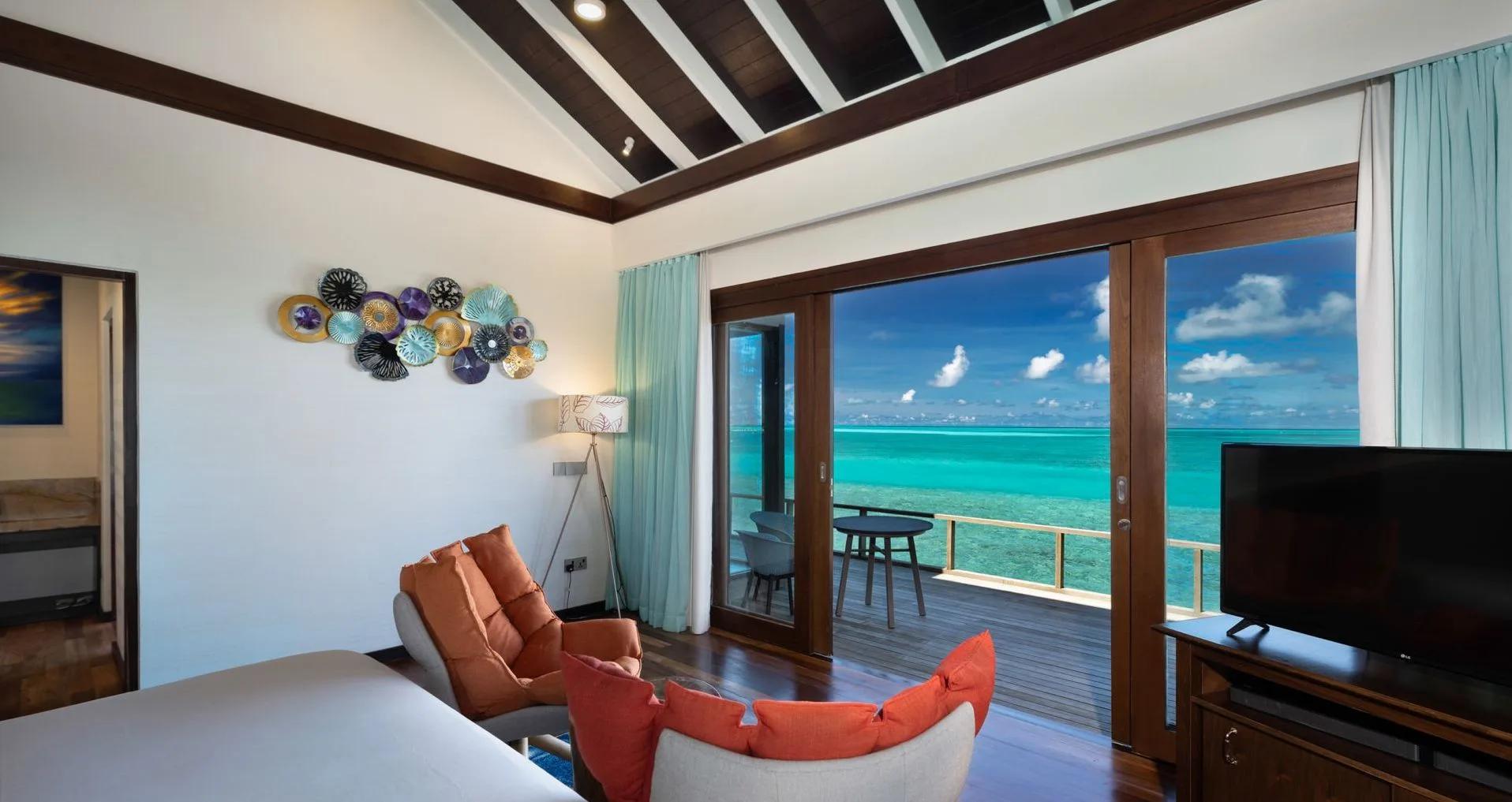 Inside a Water Villa's living area, sliding doors opening onto its deck above the lagoon