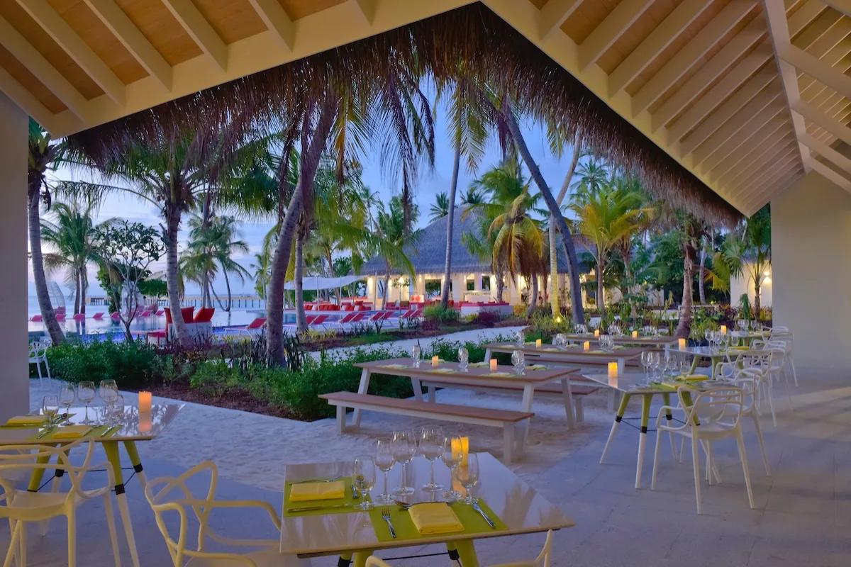 Flavour Zest's garden seating set for dinner at dusk, with the pool and lagoon visible beyond