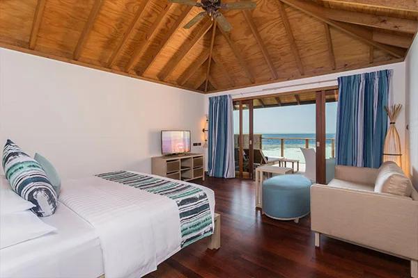 Romantic Ocean Villa bedroom by daylight, doors open to the private overwater deck