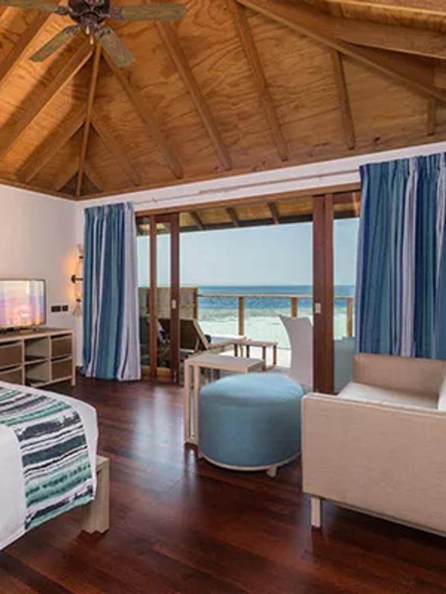 Romantic Ocean Villa bedroom by daylight, doors open to the private overwater deck