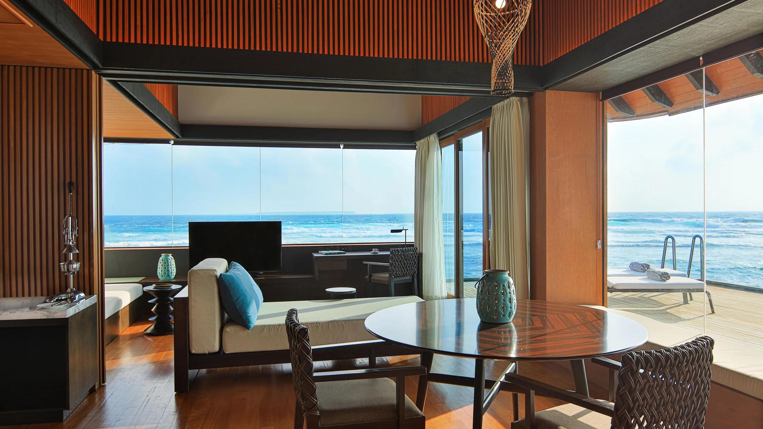 The open living and bedroom space of a Heavenly Overwater Villa, ocean visible on both sides