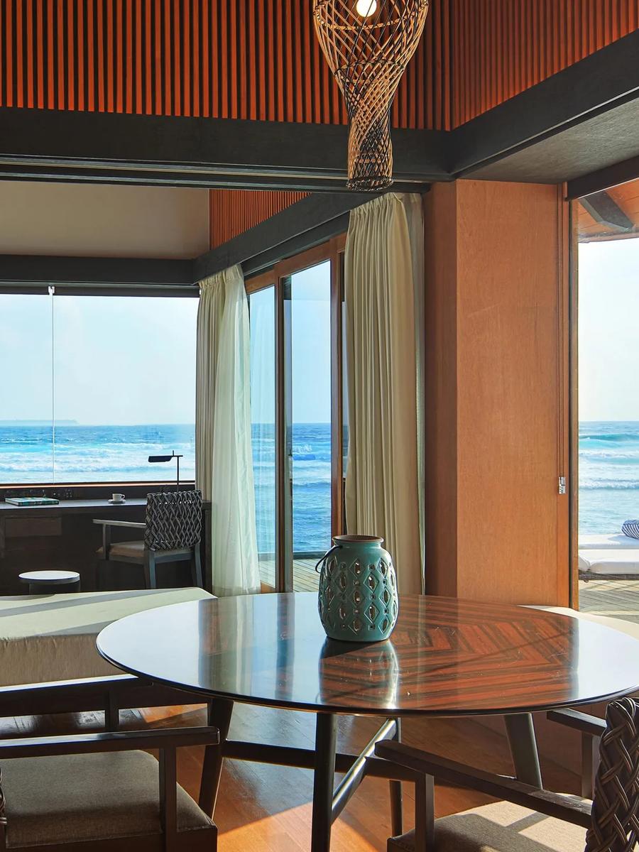 The open living and bedroom space of a Heavenly Overwater Villa, ocean visible on both sides