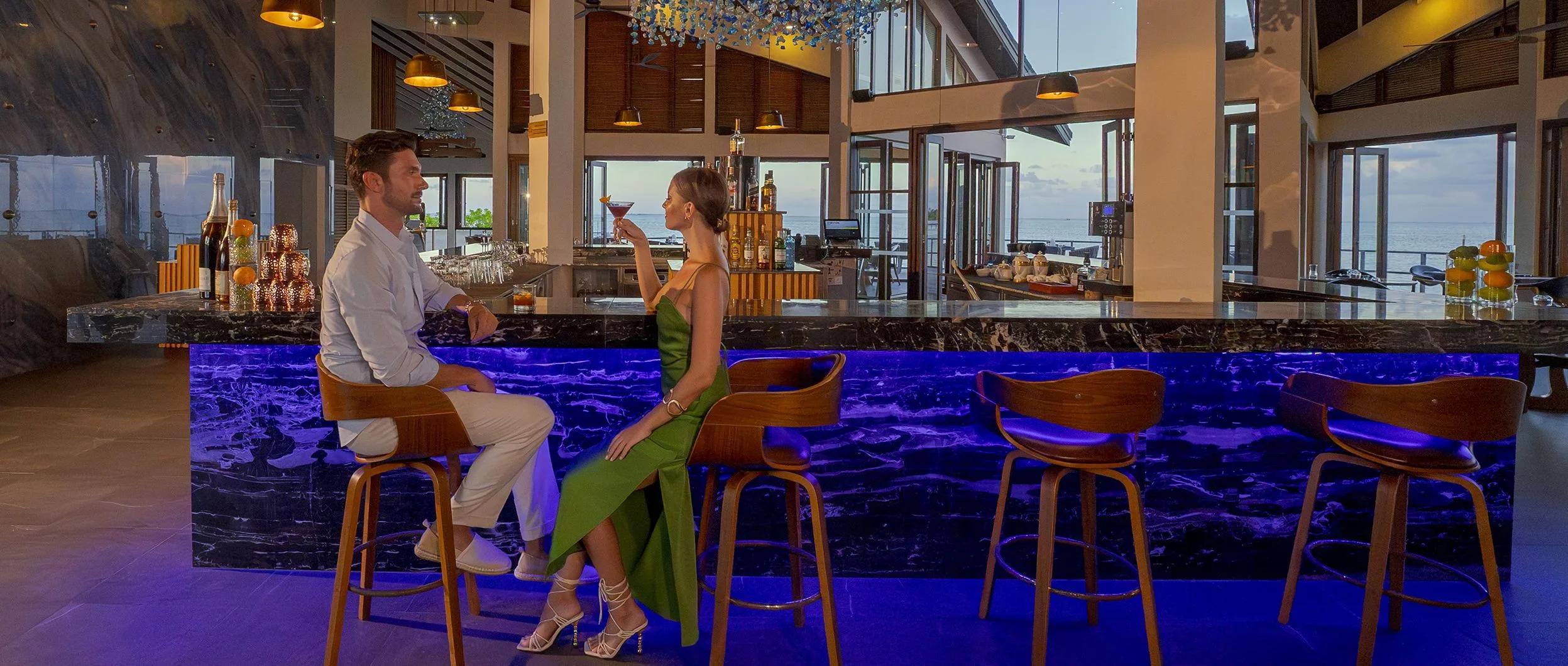 Pier Six's bar, dining tables visible beyond, built out over the lagoon on its own peninsula at dusk