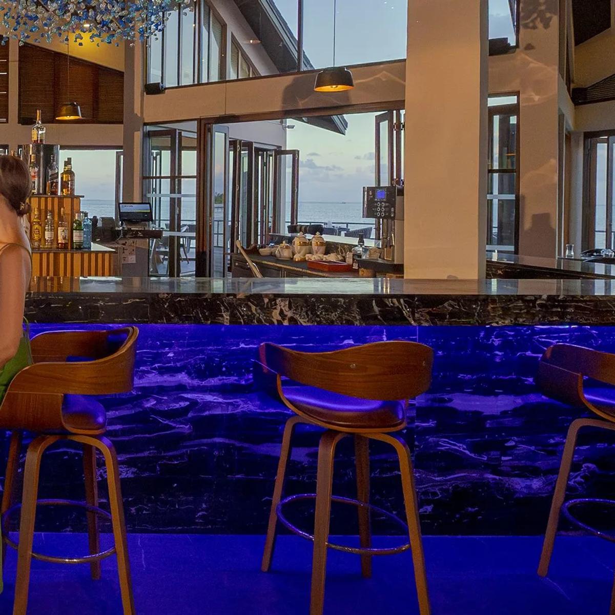 Pier Six's bar, dining tables visible beyond, built out over the lagoon on its own peninsula at dusk