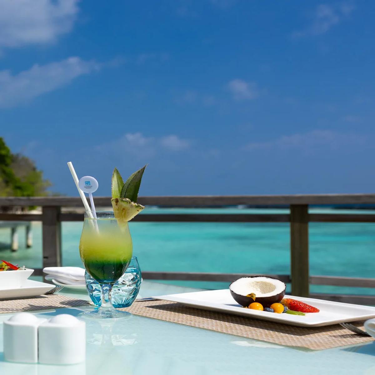 Cocktails and a plate of fries and fish goujons on a table at Sea Breeze, the jetty and lagoon visible beyond the rail