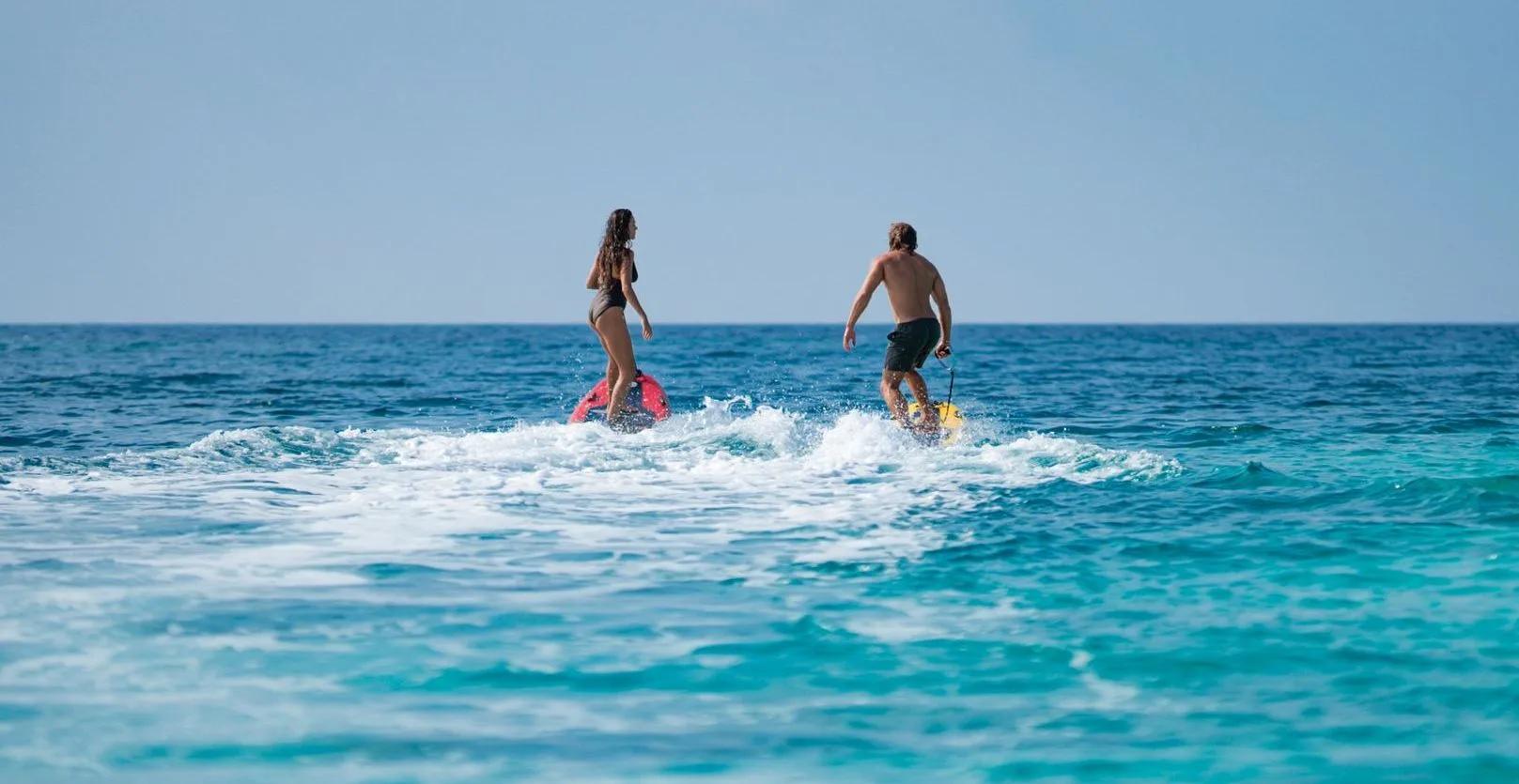 Two guests riding motorised watersports boards across the lagoon at OBLU SELECT Lobigili