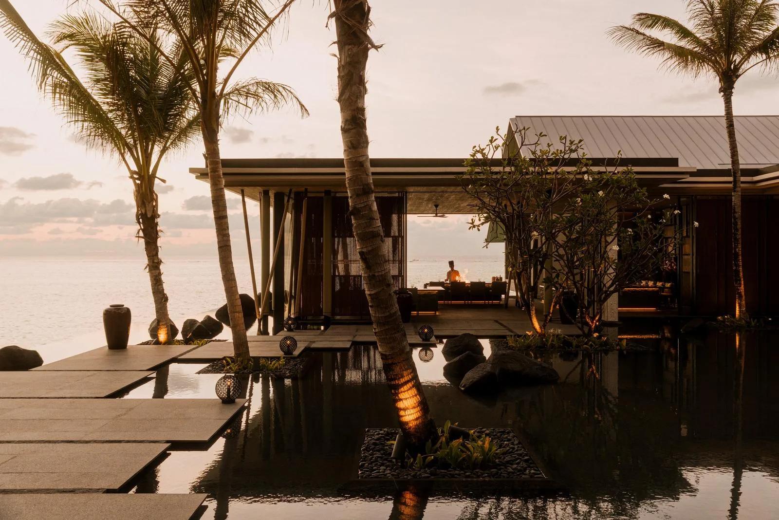 A chef cooks at an open-air grill at sunset beside a reflecting pool at One&Only Reethi Rah — standing in for Hoshi, the resort's omakase restaurant reached by boat, since no dedicated Hoshi photograph was collected