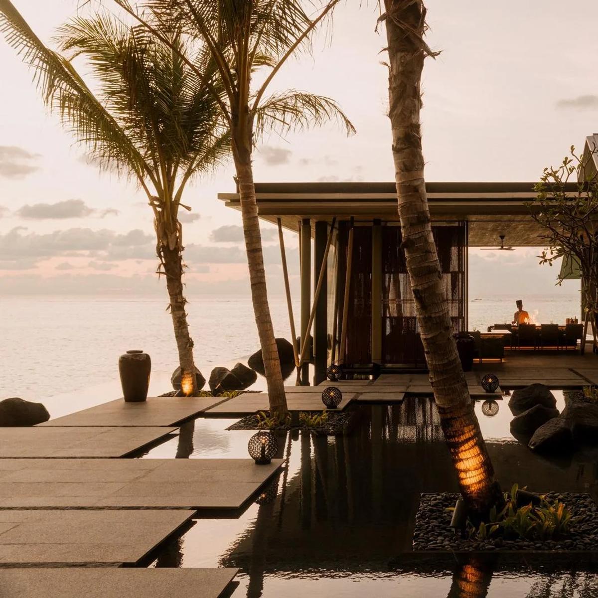 A chef cooks at an open-air grill at sunset beside a reflecting pool at One&Only Reethi Rah — standing in for Hoshi, the resort's omakase restaurant reached by boat, since no dedicated Hoshi photograph was collected