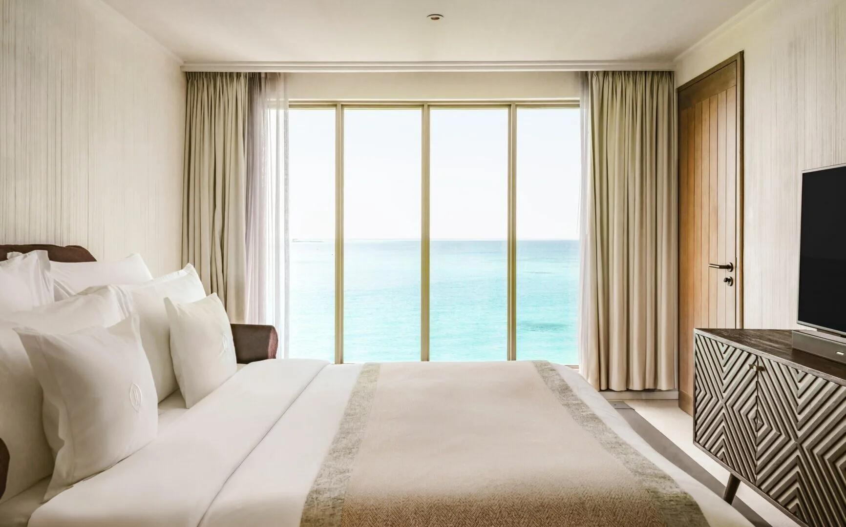 The upper-floor bedroom of a two-storey Lagoon Villa, floor-to-ceiling windows over the lagoon