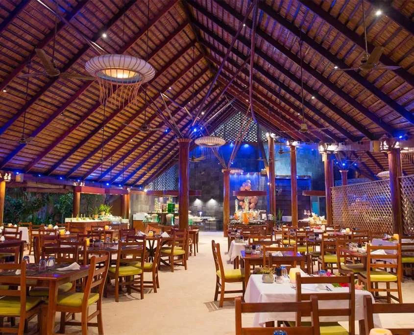 Bonthi Restaurant's thatched dining hall lit blue after dark, tables set for dinner