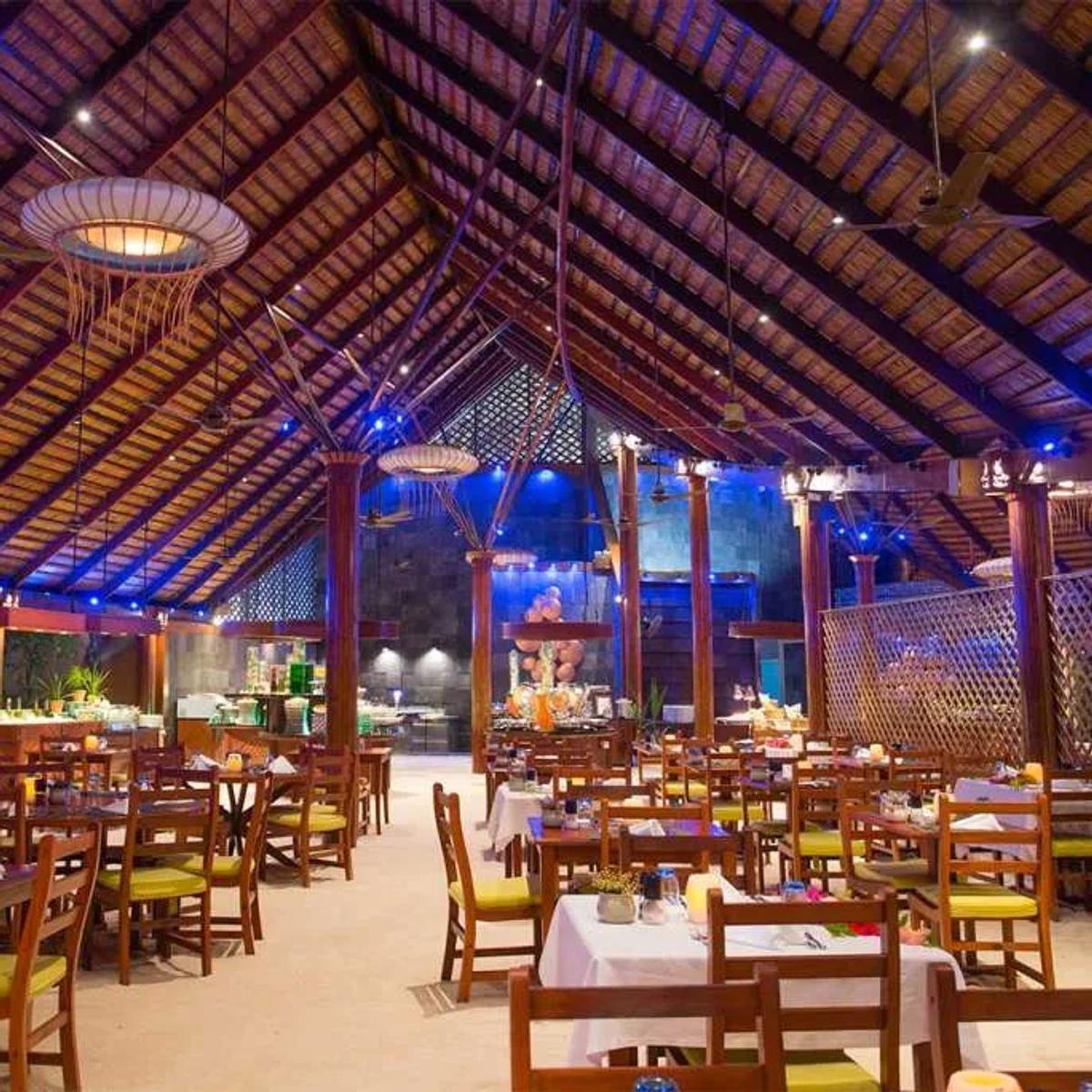 Bonthi Restaurant's thatched dining hall lit blue after dark, tables set for dinner