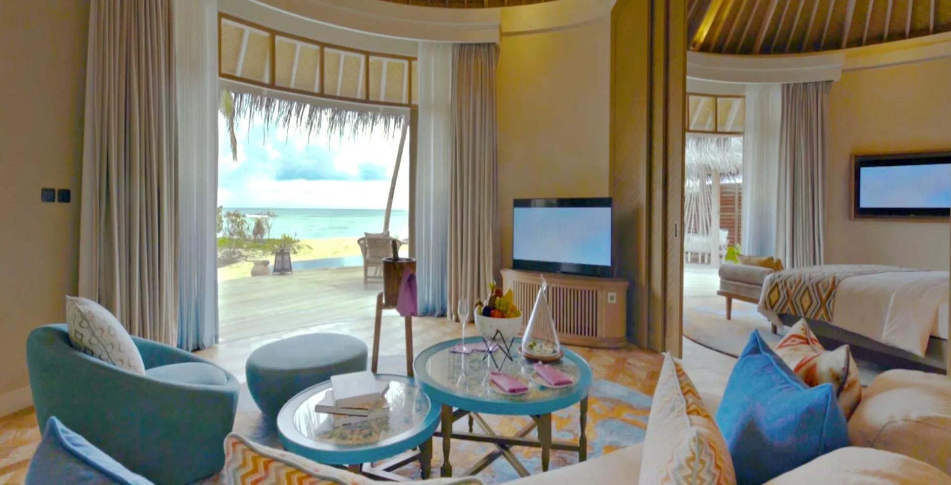 A Beach House bedroom and sitting area, its doors open to a beachfront deck and sun loungers.