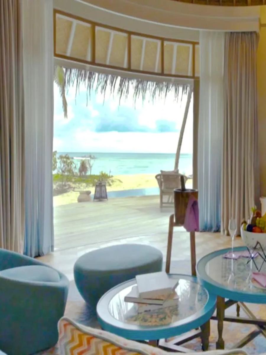 A Beach House bedroom and sitting area, its doors open to a beachfront deck and sun loungers.