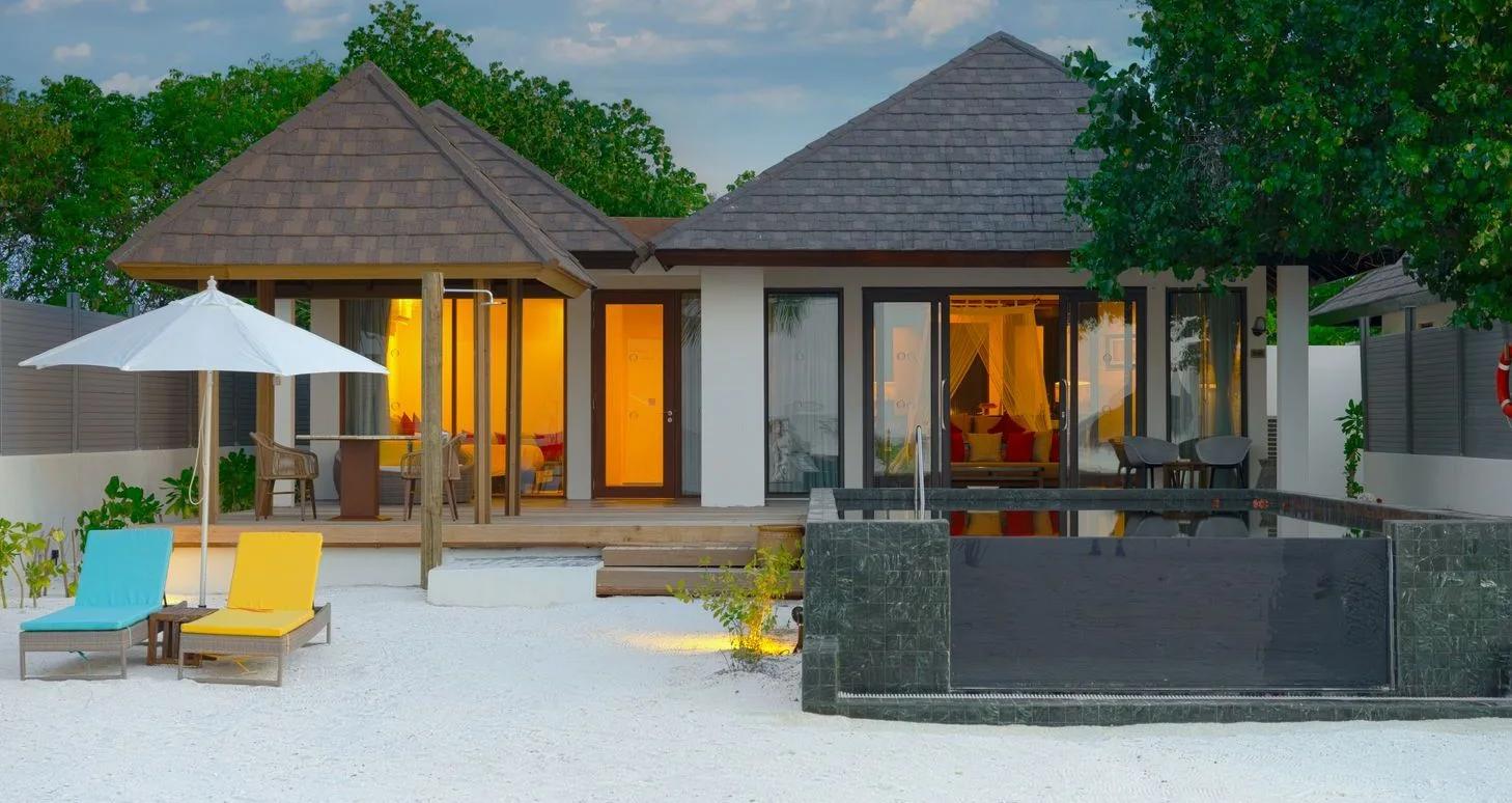 A Two Bedroom Sunset Family Beach Villa with Pool at dusk, its private pool lit beside the twin-roofed duplex