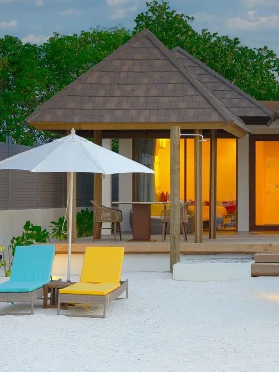 A Two Bedroom Sunset Family Beach Villa with Pool at dusk, its private pool lit beside the twin-roofed duplex