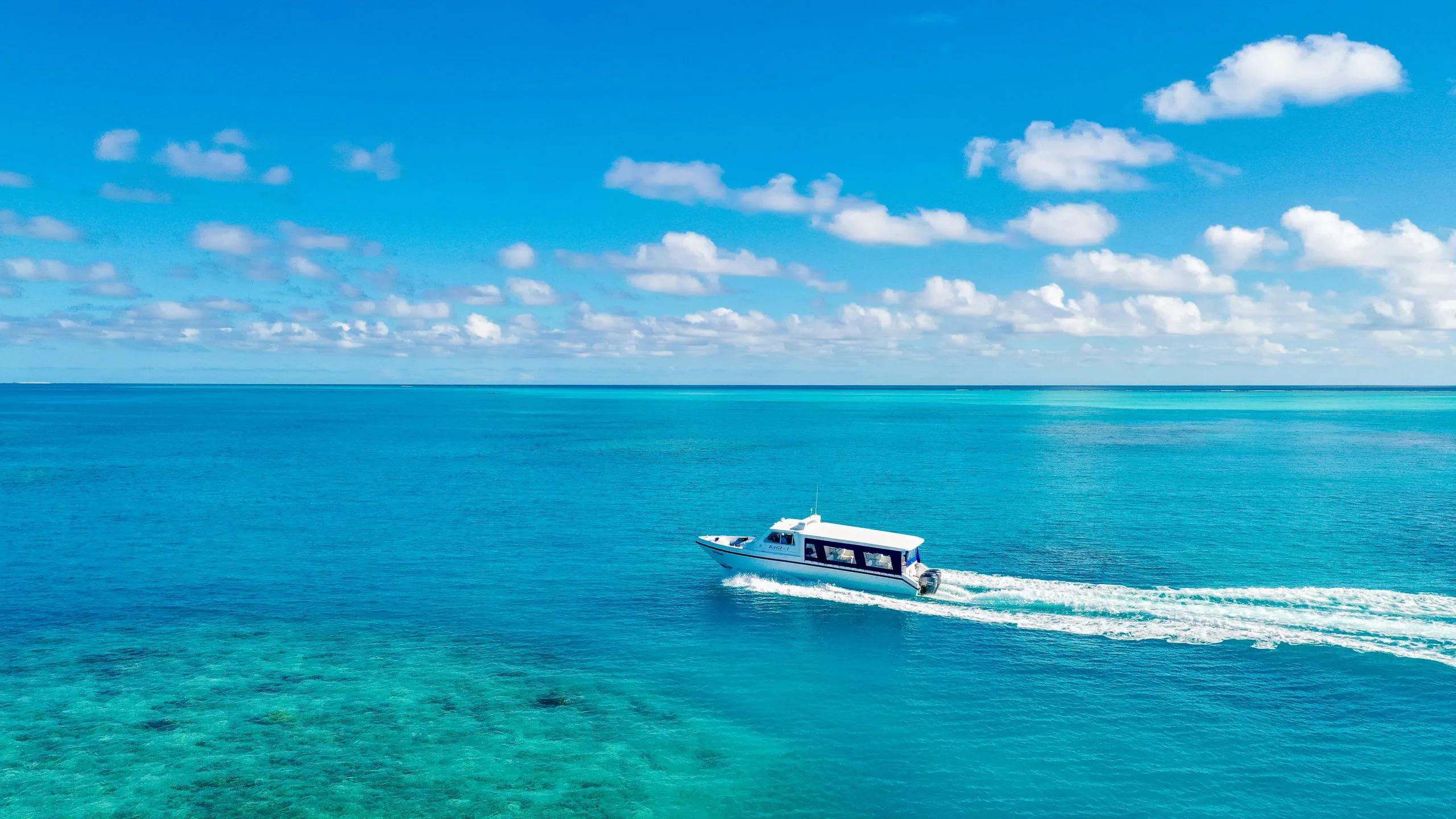 Kagi's own speedboat, Kagi-1, crossing open water with reef visible beneath the surface