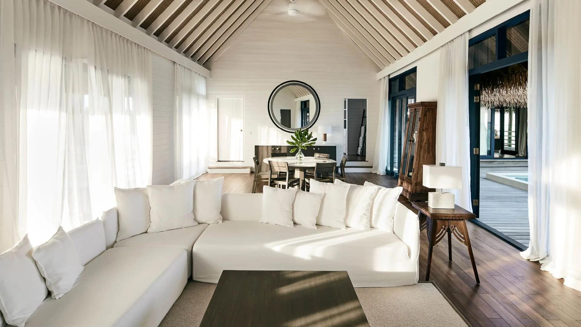 The shared living and dining space of the Two-Bedroom COMO Sunrise Villa, with a round table beneath a vaulted ceiling
