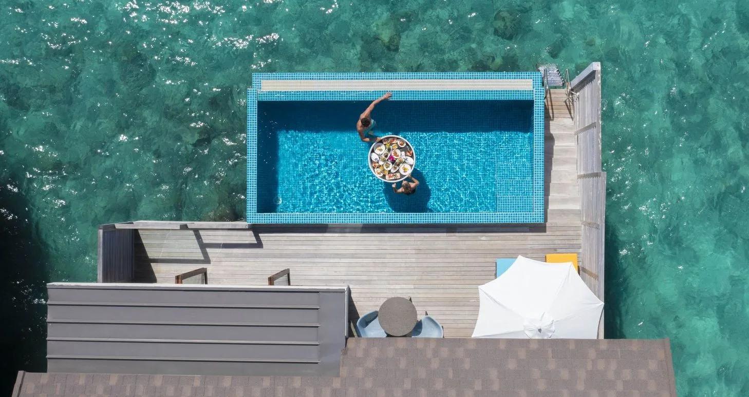 A private plunge pool over the lagoon at a Sunset Water Villa with Pool, breakfast floated between two swimmers