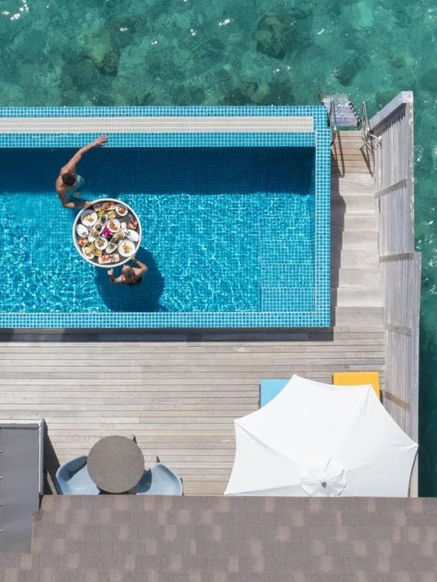 A private plunge pool over the lagoon at a Sunset Water Villa with Pool, breakfast floated between two swimmers