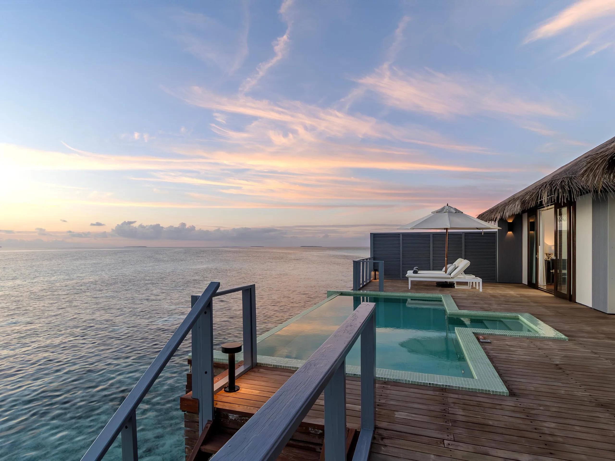 Sunset over the private pool deck of an overwater villa at Noku Maldives