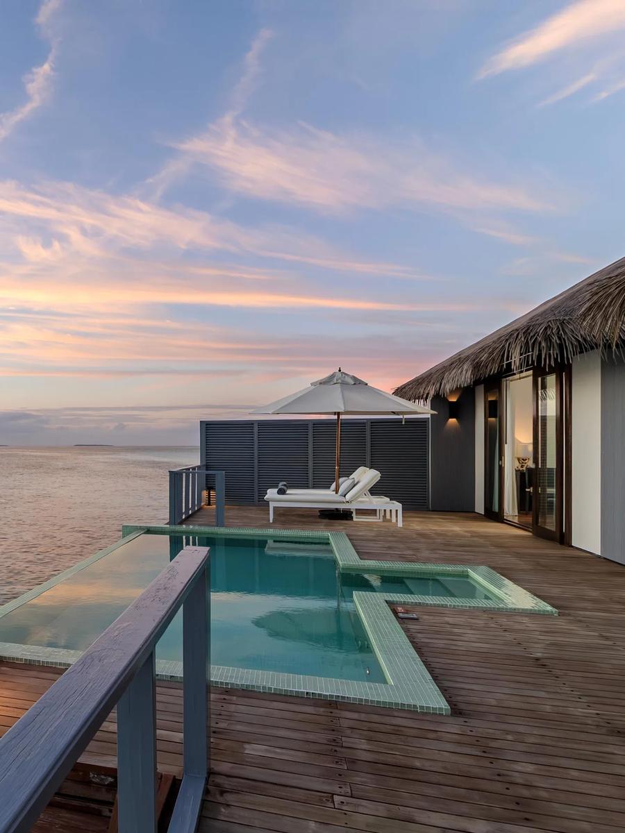 Sunset over the private pool deck of an Overwater Villa at Noku Maldives, open sea stretching to the horizon