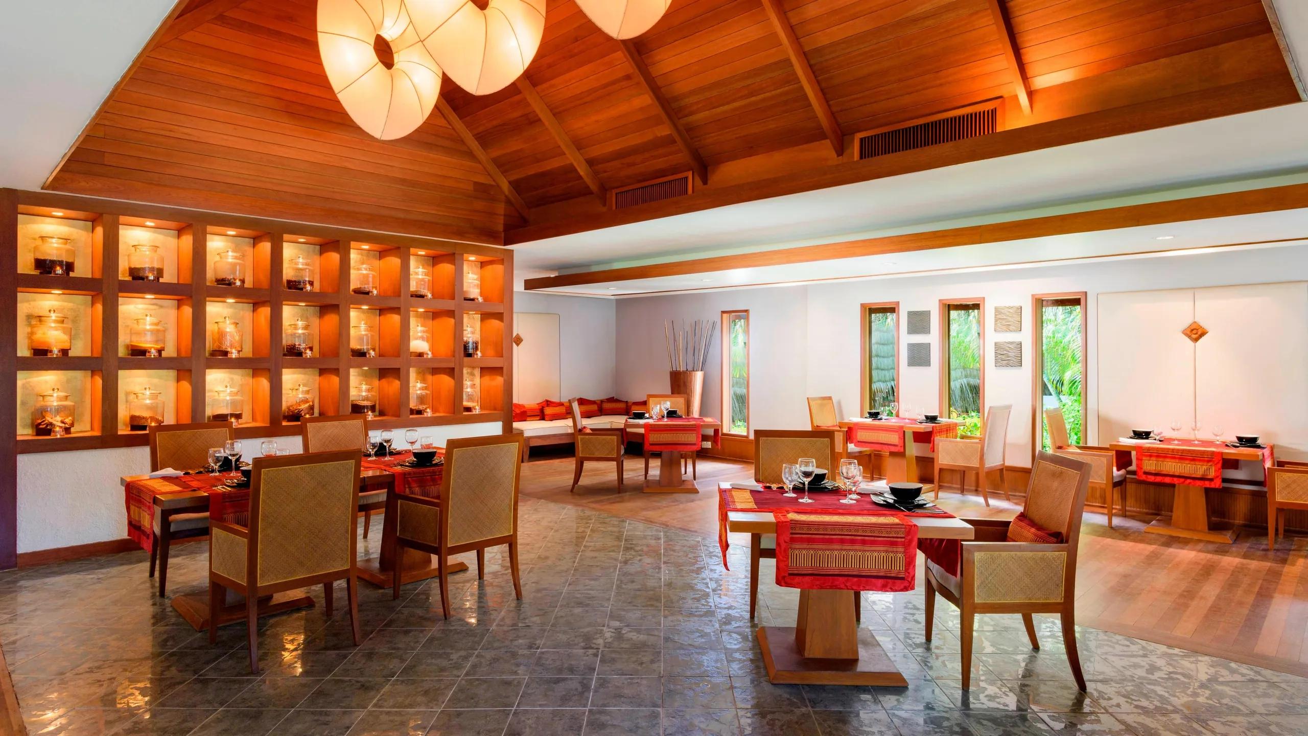 Baan Thai's dining room, with a lit display wall of glass jars and red table settings