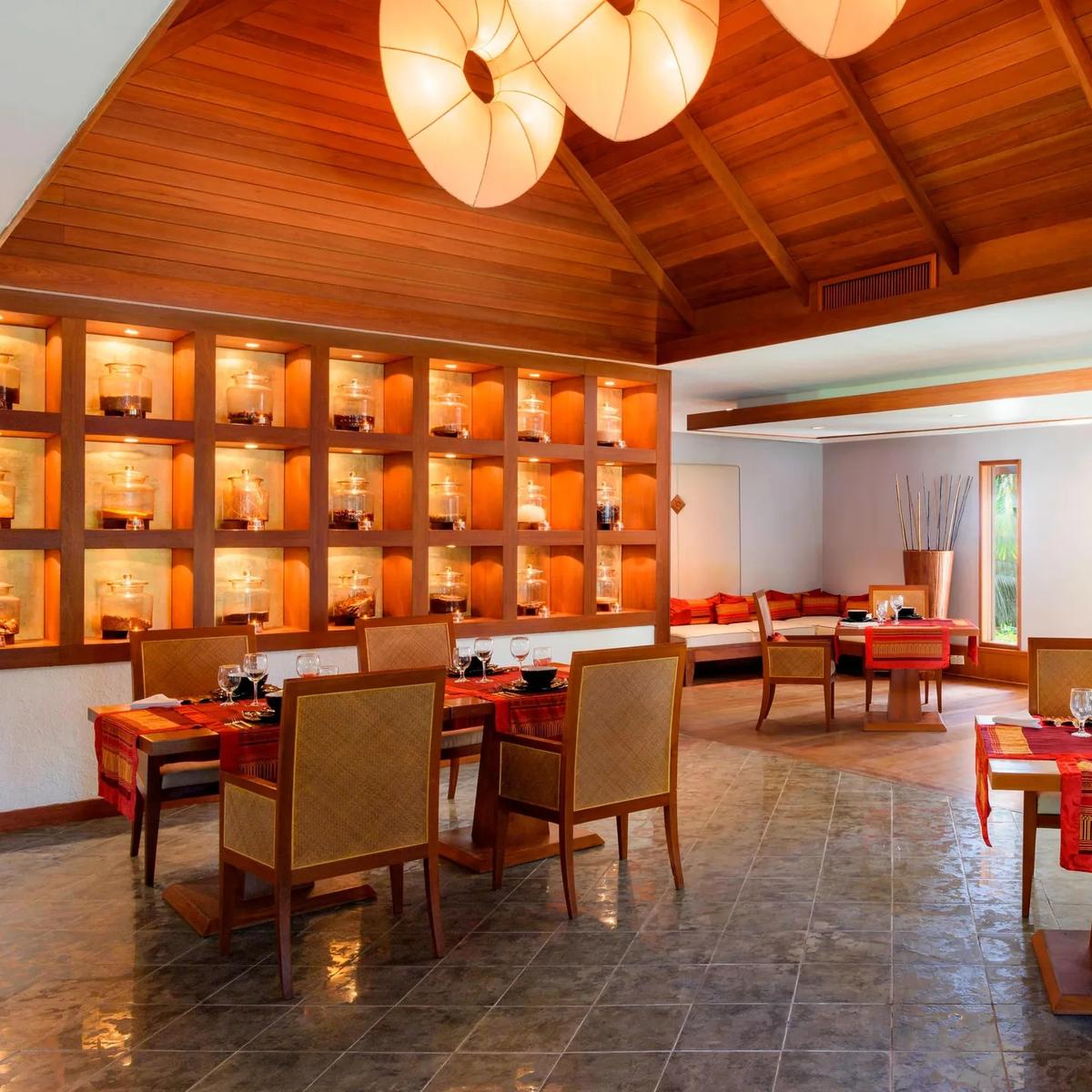 Baan Thai's dining room, with a lit display wall of glass jars and red table settings