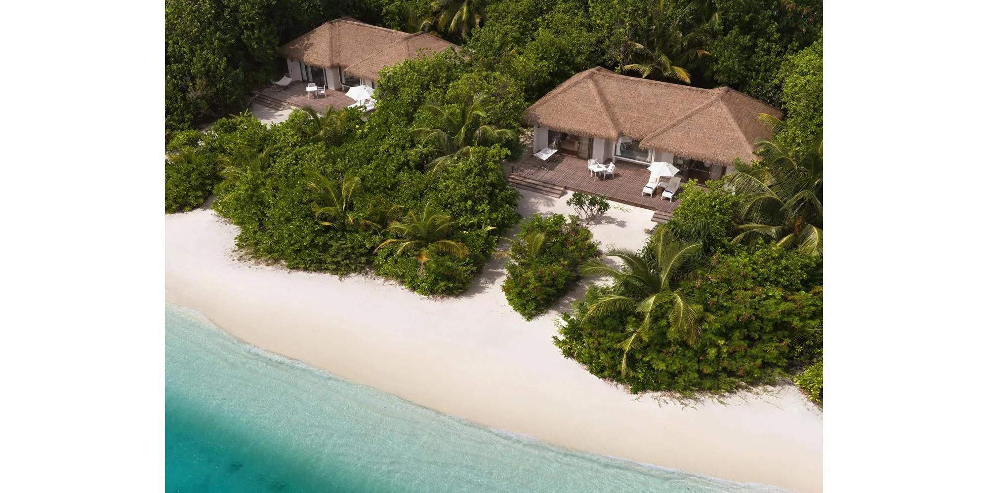 Two beach villas at Noku Maldives, tucked into palm greenery just off the sand