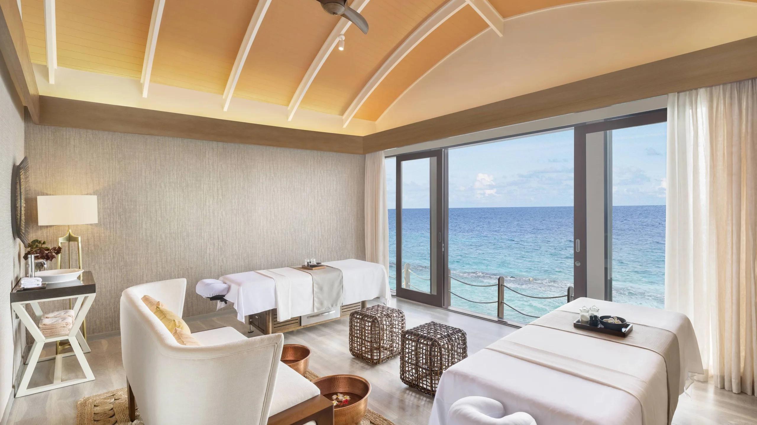 The spa's relaxation lounge, two loungers beside a private plunge pool with ocean views