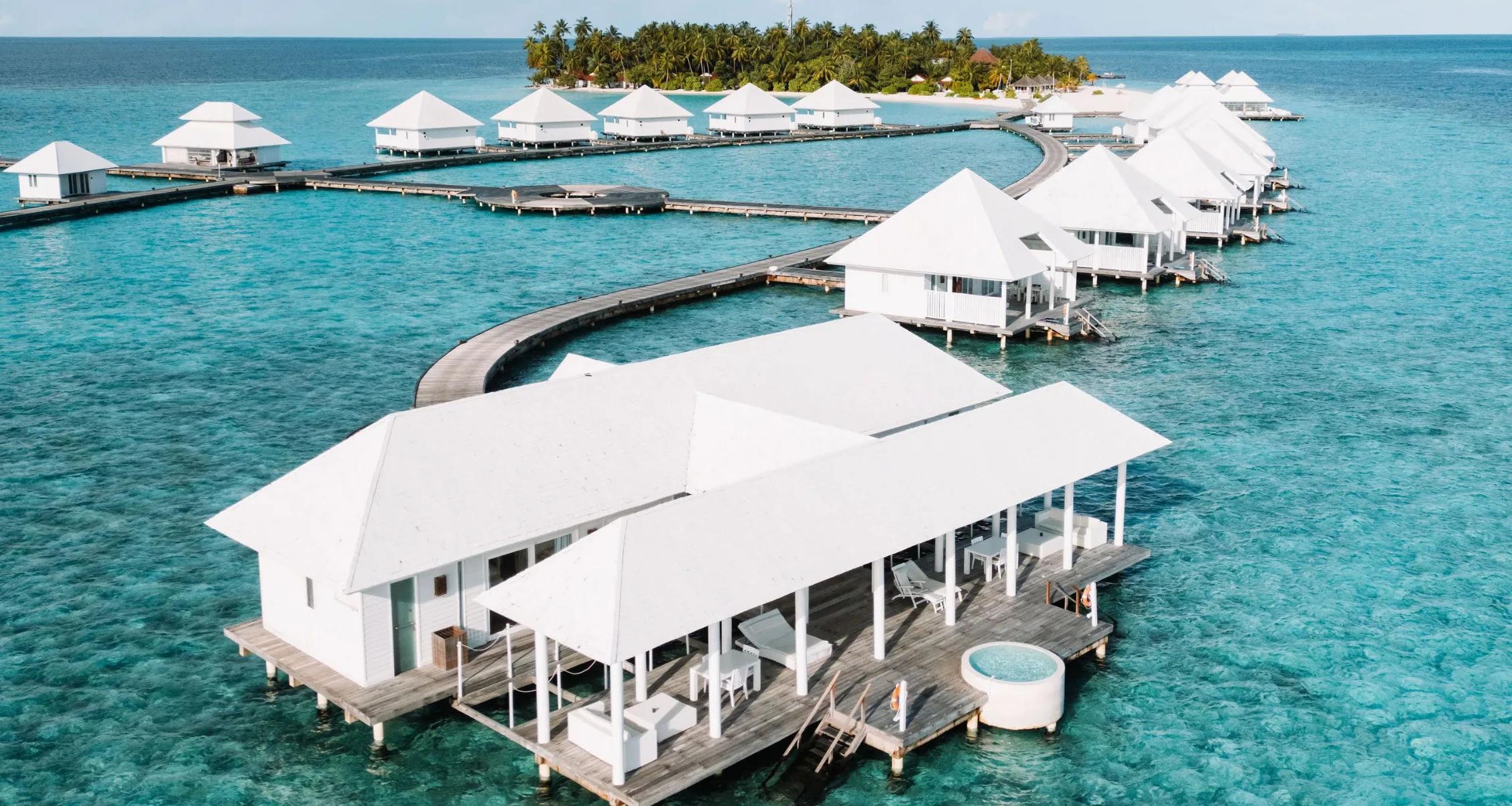 Aerial view of the water villa jetty at Diamonds Athuruga, island in the background