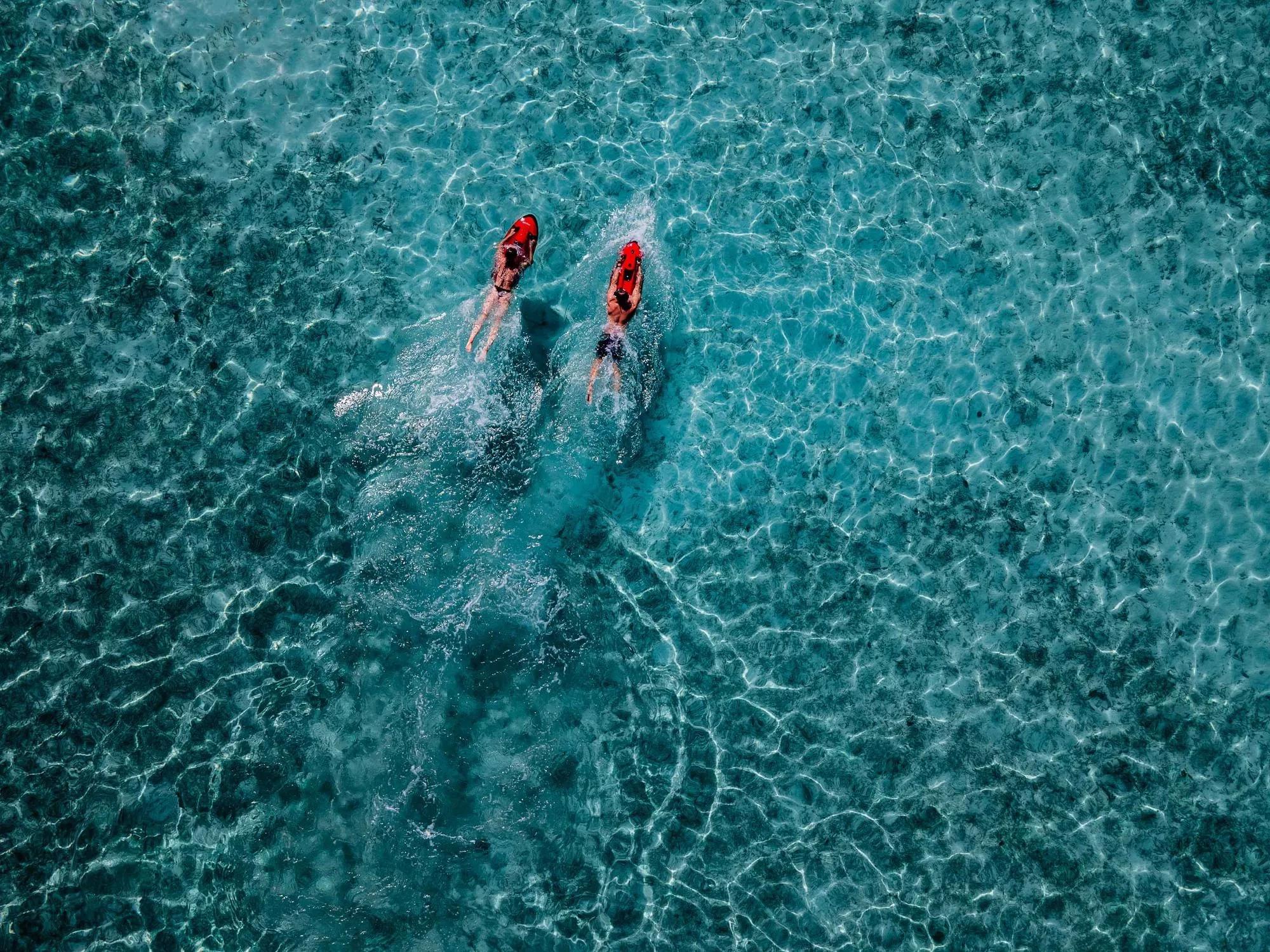 An aerial view of the turquoise water surrounding Ifuru Island Maldives, a seabob rider visible below