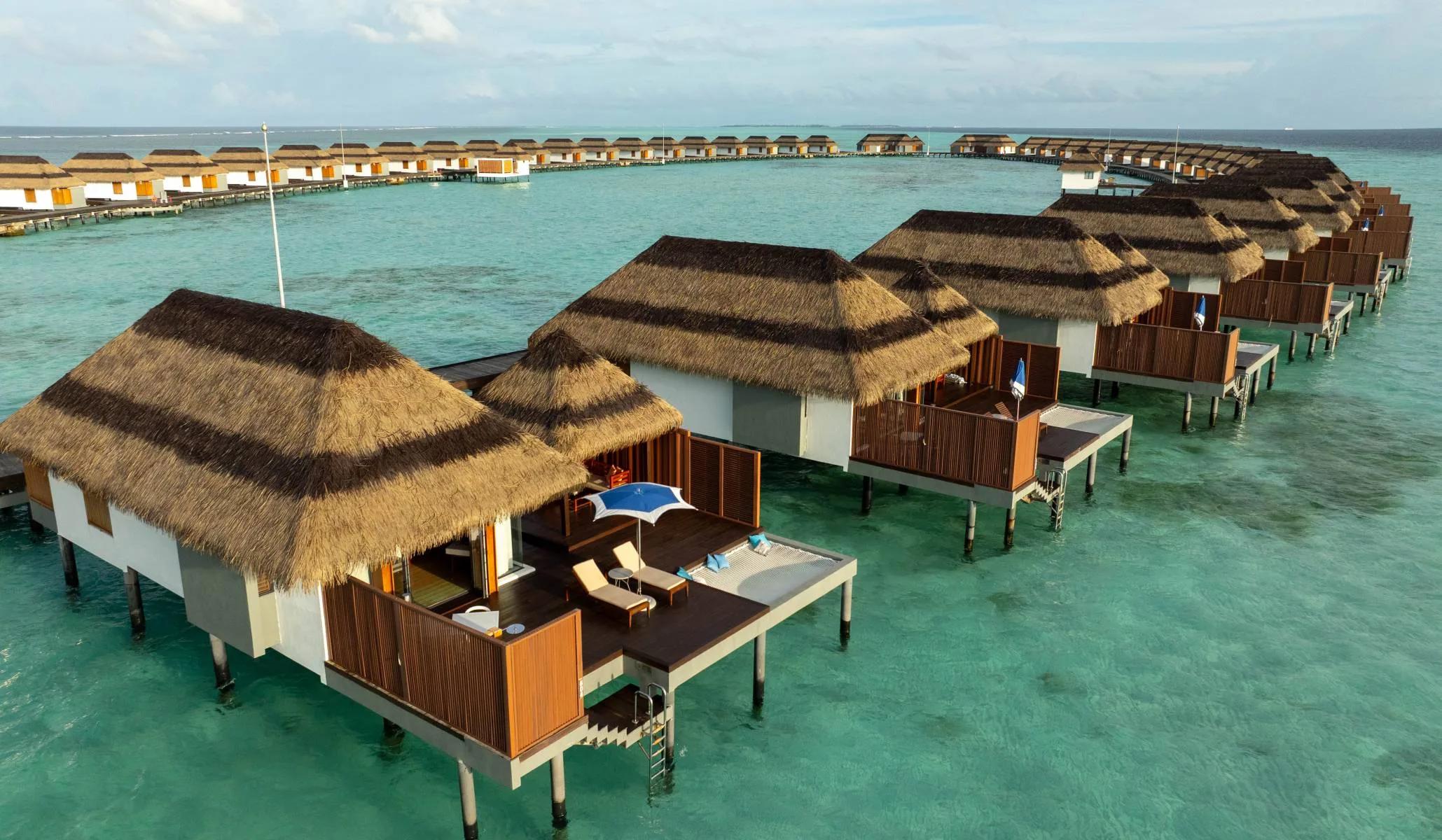 An aerial view of Ocean Villas extending from the island over the lagoon at Pullman Maldives Maamutaa