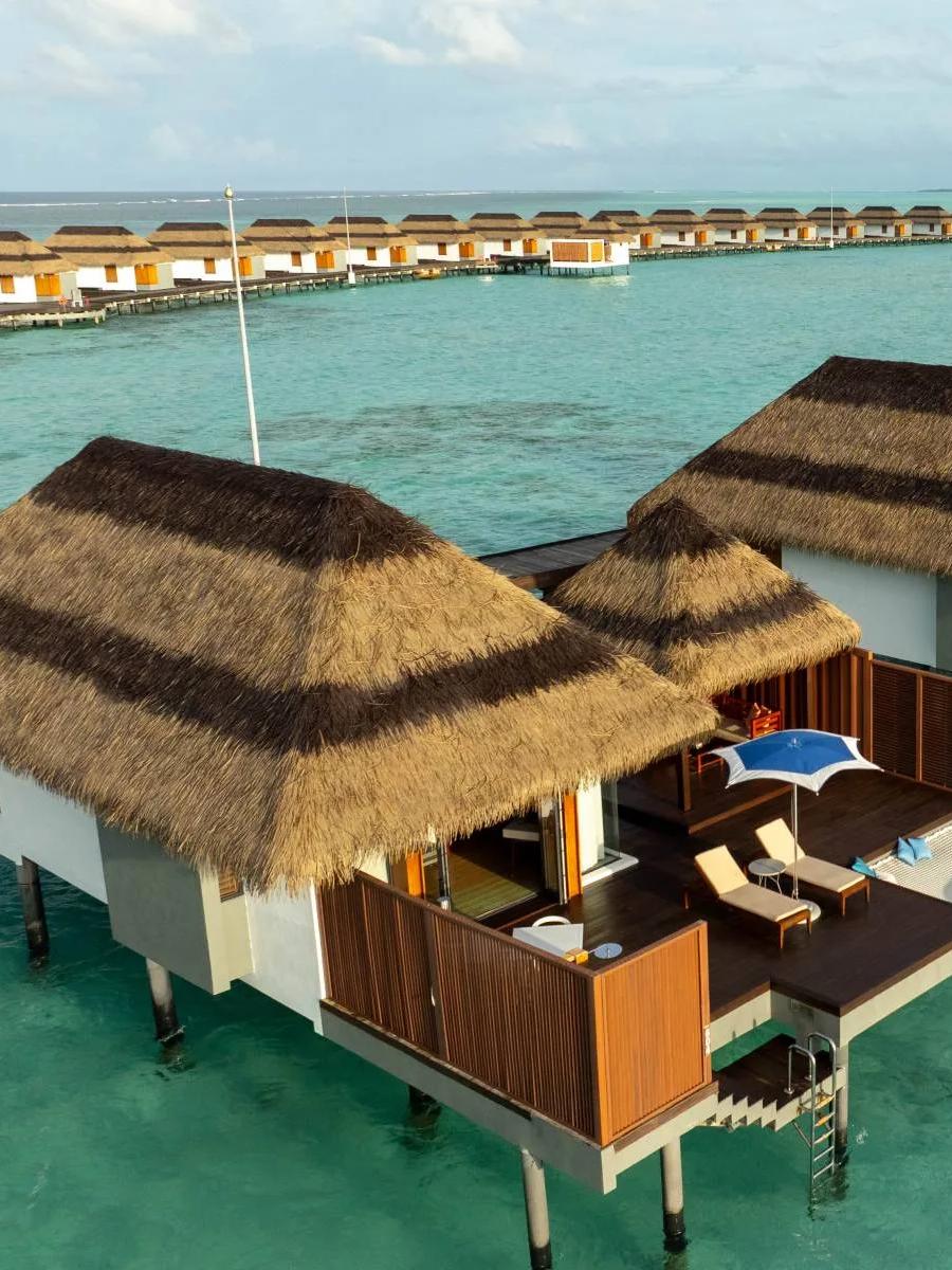An aerial view of Ocean Villas extending from the island over the lagoon at Pullman Maldives Maamutaa