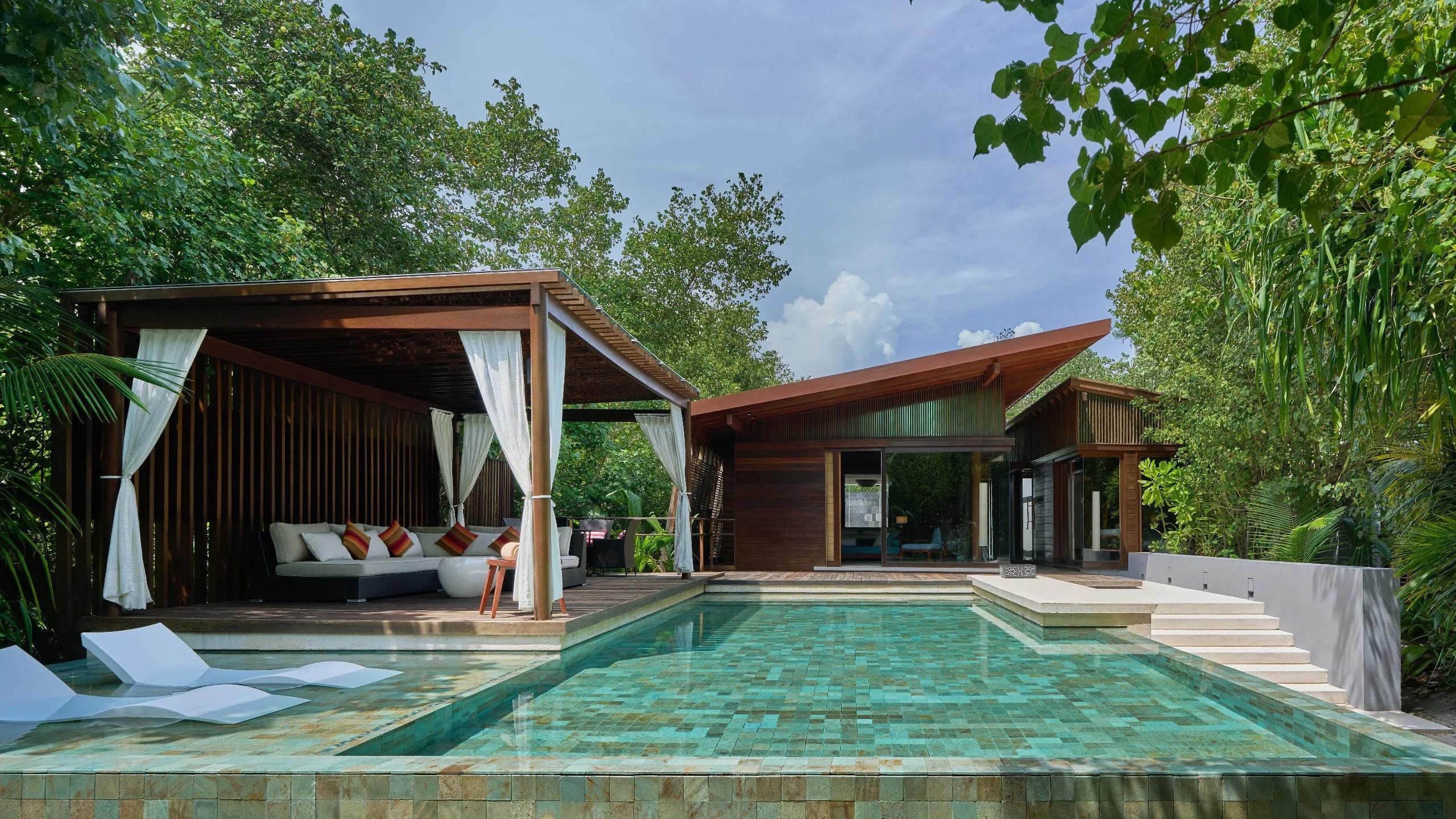The pool deck and curtained cabana of a Two Bedroom Beach Pool Villa
