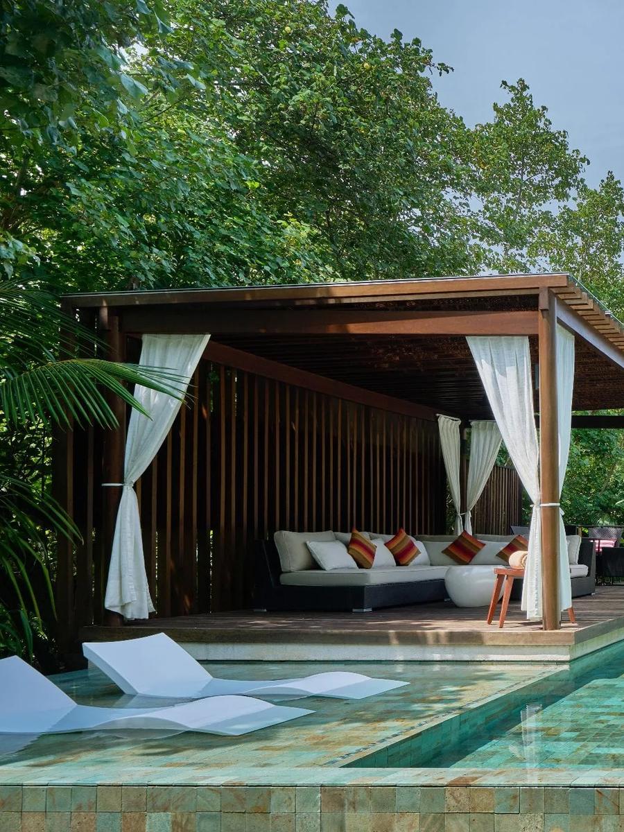The pool deck and curtained cabana of a Two Bedroom Beach Pool Villa