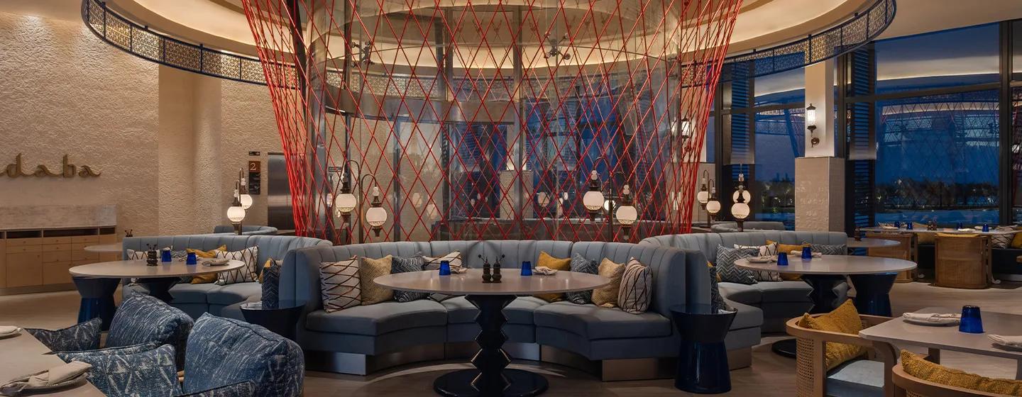 Hadaba's dining room at SO/ Maldives, blue banquette seating curved beneath a red string installation