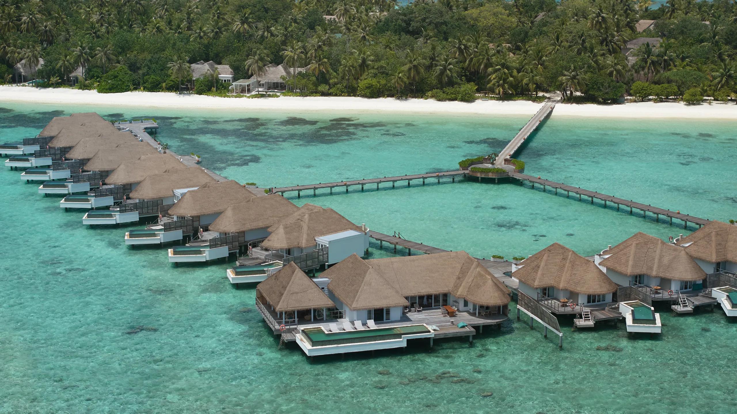 Aerial view of the resort's largest overwater villa, its thatched roof and private pool set at the end of the jetty.